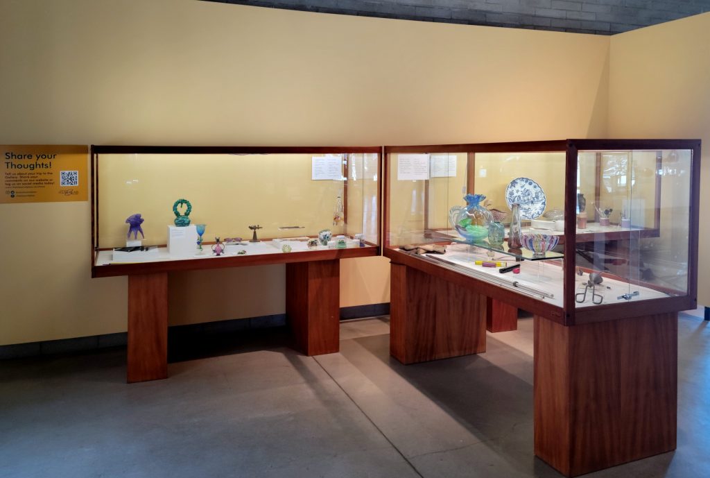 An image of display cases featuring tools and examples of clay, glass and enamel works of art. 